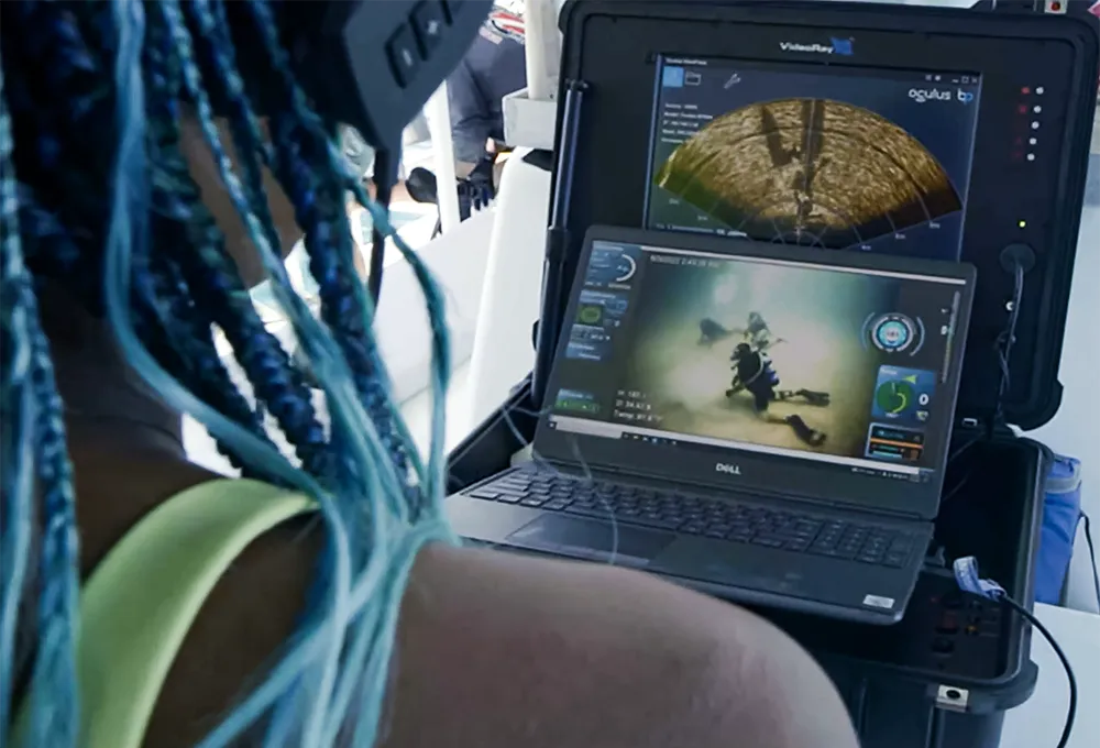 A student monitors divers underwater at a site